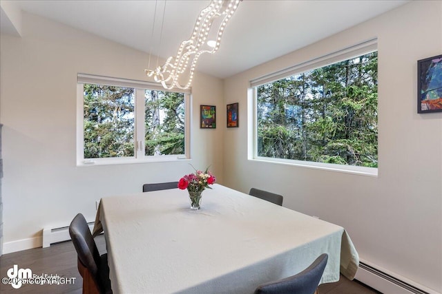 dining room with a notable chandelier, baseboard heating, plenty of natural light, and dark wood-type flooring