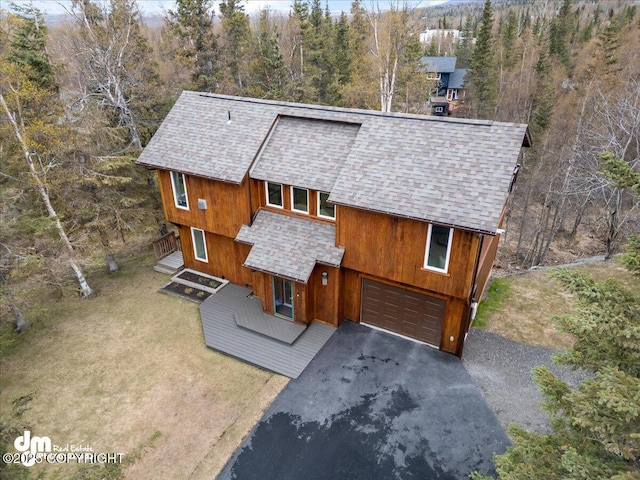 chalet / cabin featuring roof with shingles, an attached garage, and driveway