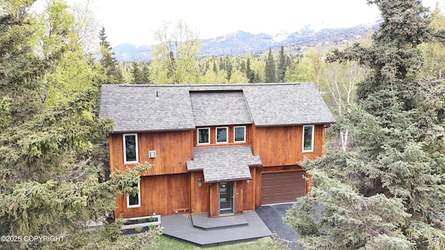 6816 Round Tree Dr, Anchorage, AK 99507 - back of property featuring a shingled roof, an attached garage, a forest view, and a mountain view