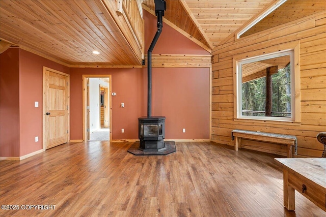unfurnished living room with a wood stove, baseboards, wood finished floors, vaulted ceiling, and wood ceiling