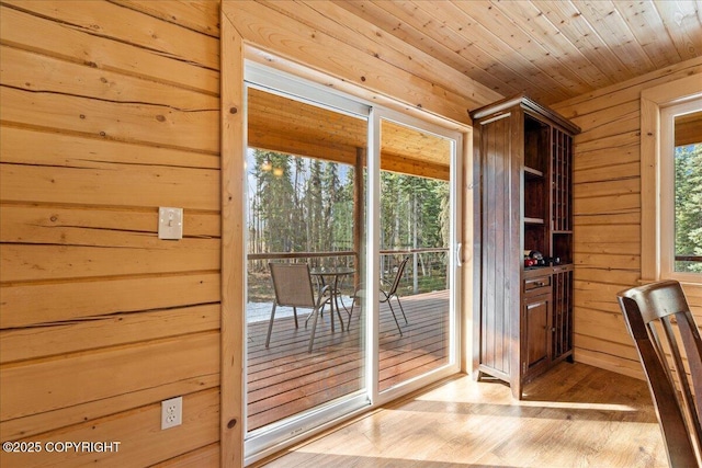 entryway with wood ceiling, light wood finished floors, and wood walls