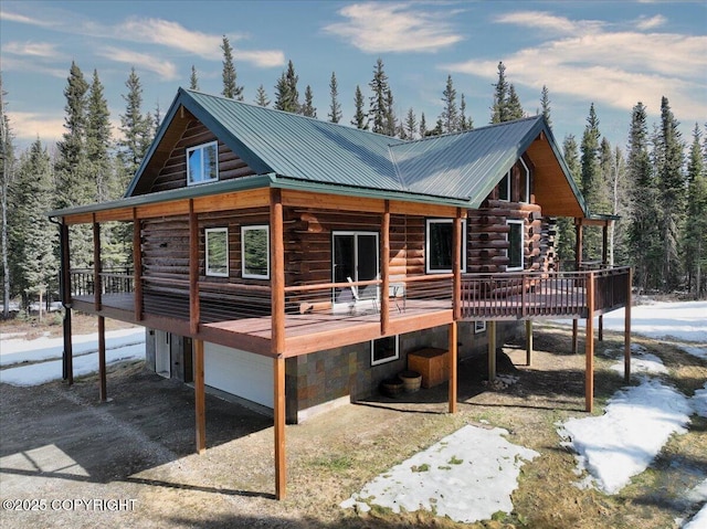 back of house with a deck, log siding, metal roof, and a garage