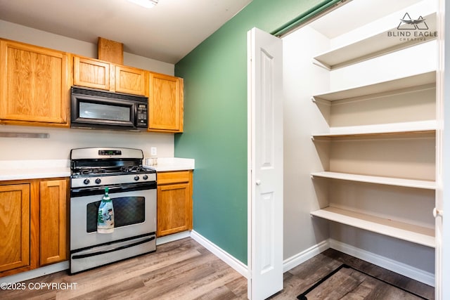 kitchen featuring gas stove, black microwave, dark wood-style floors, open shelves, and light countertops
