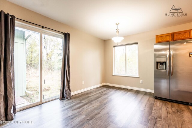 unfurnished dining area with wood finished floors and baseboards