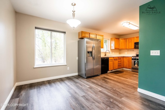 kitchen with black appliances, wood finished floors, light countertops, and baseboards