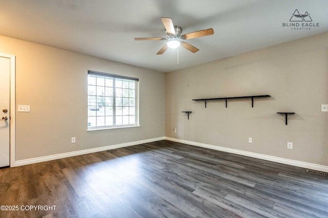 spare room with a ceiling fan, dark wood-style flooring, and baseboards