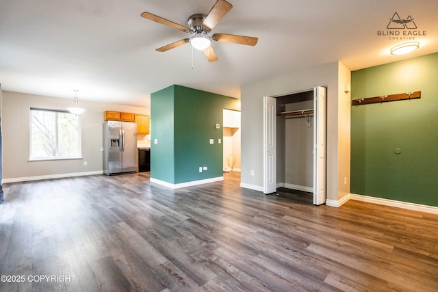 unfurnished bedroom featuring stainless steel fridge, dark wood-style flooring, baseboards, and connected bathroom