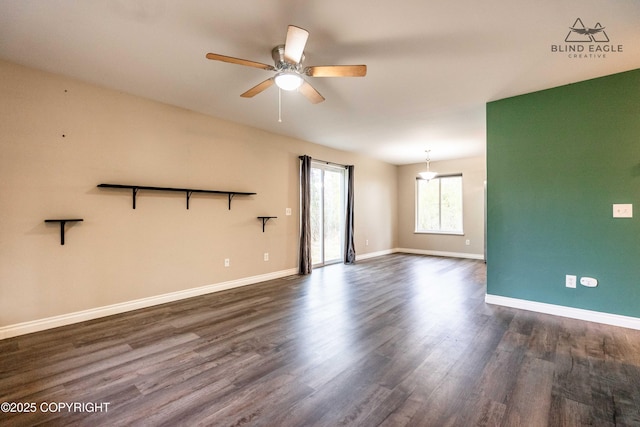 spare room with ceiling fan, dark wood-style flooring, and baseboards