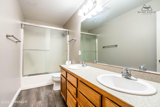 full bathroom with wood finished floors, double vanity, toilet, and combined bath / shower with glass door