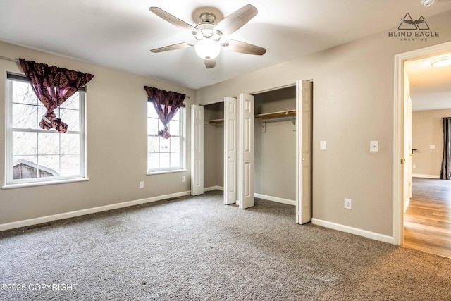 unfurnished bedroom featuring two closets, carpet, baseboards, and a ceiling fan