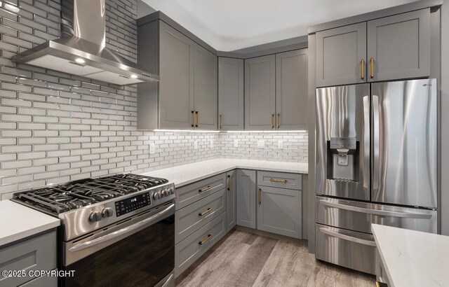 1205 N Williwaw Way, Wasilla, AK 99654 - kitchen with decorative backsplash, light countertops, wall chimney exhaust hood, gray cabinetry, and stainless steel appliances