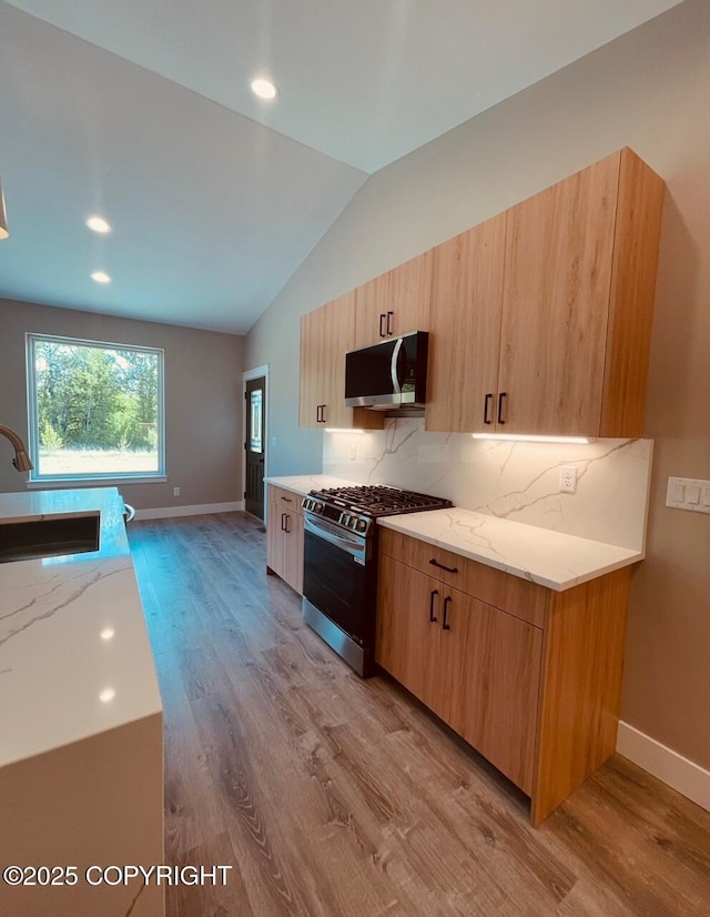 1205 N Williwaw Way, Wasilla, AK 99654 - kitchen featuring appliances with stainless steel finishes, light wood finished floors, vaulted ceiling, tasteful backsplash, and light stone counters