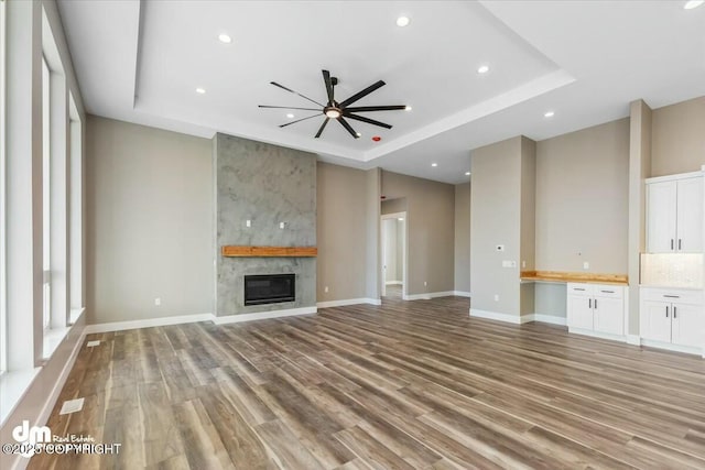 2600 S Sanctuary Dr, Wasilla, AK 99654 - unfurnished living room featuring a tray ceiling, light wood-style floors, a ceiling fan, a fireplace, and recessed lighting