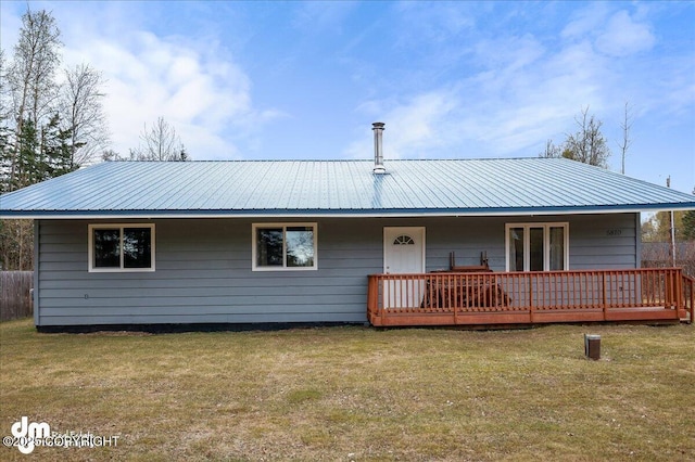 rear view of property featuring a lawn, a deck, and metal roof