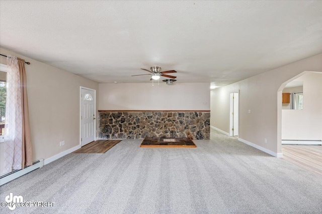 unfurnished living room featuring a ceiling fan, arched walkways, baseboard heating, carpet floors, and a baseboard heating unit