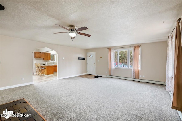 unfurnished living room featuring light colored carpet, a textured ceiling, a ceiling fan, baseboards, and a baseboard radiator