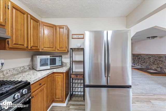 kitchen featuring light countertops, brown cabinetry, stainless steel appliances, and a textured ceiling