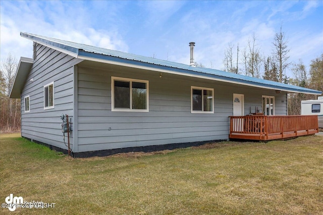 rear view of property featuring a lawn, metal roof, and a wooden deck