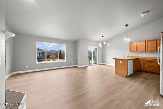 kitchen with white dishwasher, a peninsula, a sink, and open floor plan