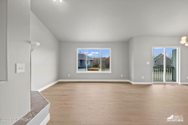 unfurnished living room featuring wood-type flooring, baseboards, and a wealth of natural light