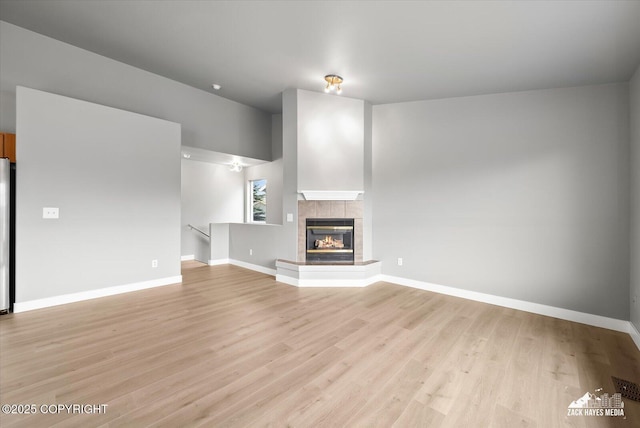 unfurnished living room featuring baseboards, light wood finished floors, and a fireplace