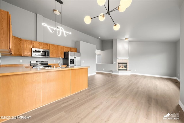kitchen with a peninsula, high vaulted ceiling, light countertops, a chandelier, and stainless steel appliances