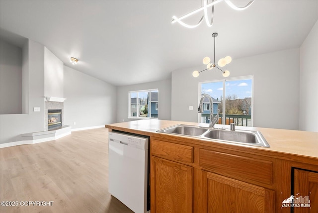 kitchen featuring brown cabinets, white dishwasher, a sink, light wood-style flooring, and lofted ceiling
