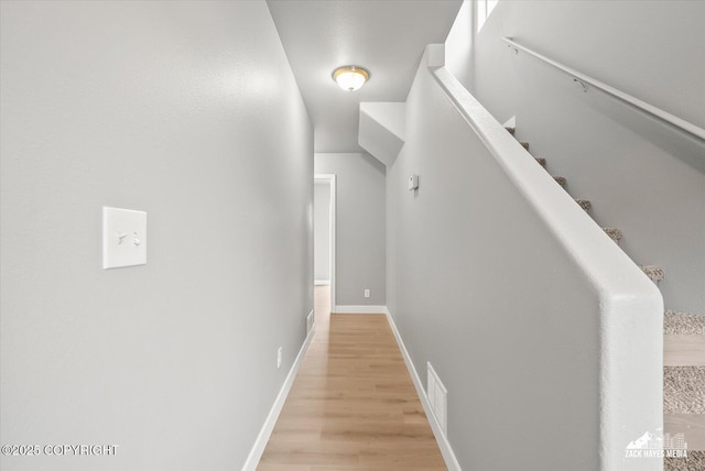 corridor featuring light wood-style floors, baseboards, and visible vents