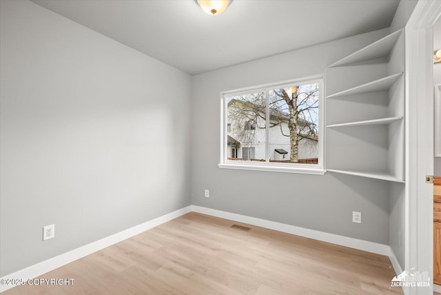 spare room with visible vents, baseboards, and wood finished floors
