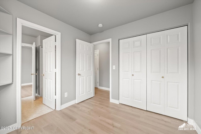 unfurnished bedroom featuring a closet, baseboards, and light wood-type flooring