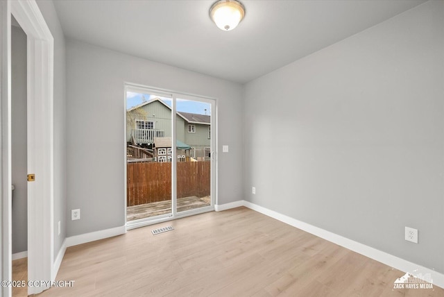 unfurnished room with baseboards, visible vents, and wood finished floors