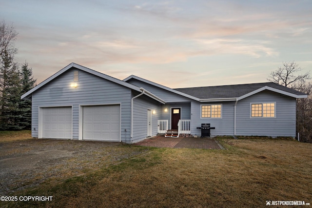 ranch-style house featuring roof with shingles, an attached garage, a yard, and driveway