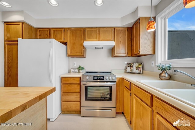 3294 Montpelier Ct # 12-E, Anchorage, AK 99503 - kitchen with stainless steel electric stove, under cabinet range hood, freestanding refrigerator, pendant lighting, and brown cabinetry