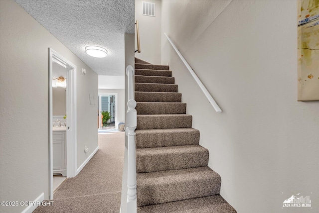 3294 Montpelier Ct # 12-E, Anchorage, AK 99503 - staircase featuring carpet flooring, a textured ceiling, and baseboards