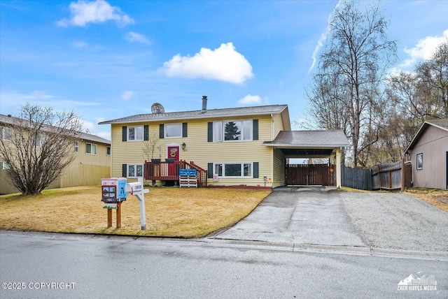 raised ranch with fence, a carport, a front yard, and aphalt driveway