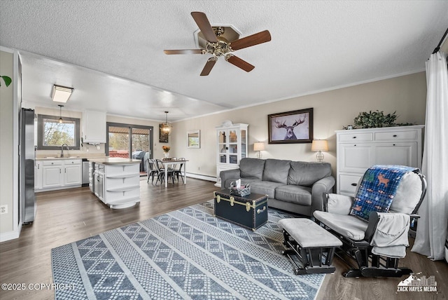 living room with ornamental molding, a ceiling fan, dark wood-style flooring, and a textured ceiling