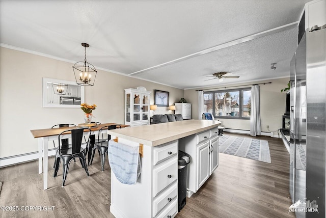 kitchen with crown molding, a kitchen island, dark wood-style floors, light countertops, and white cabinetry