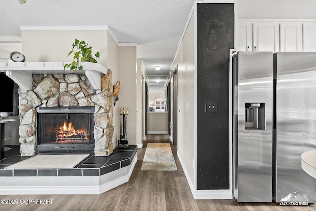 interior space with ornamental molding, a textured ceiling, wood finished floors, and a fireplace
