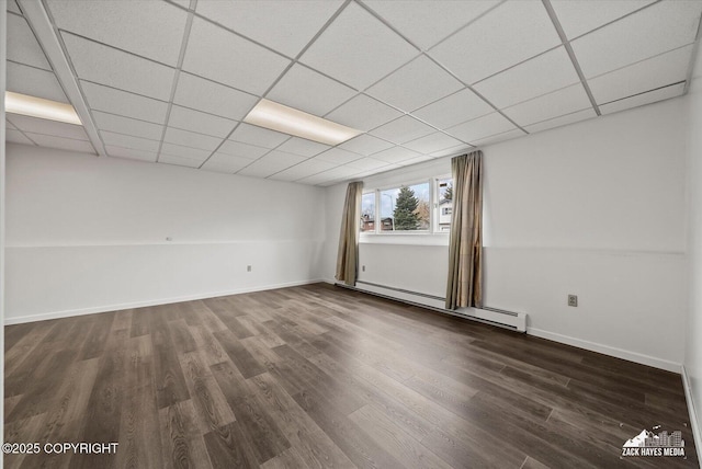 empty room with dark wood-style flooring, baseboards, a drop ceiling, and baseboard heating