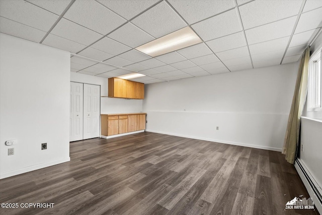 below grade area with baseboards, baseboard heating, and dark wood-style flooring