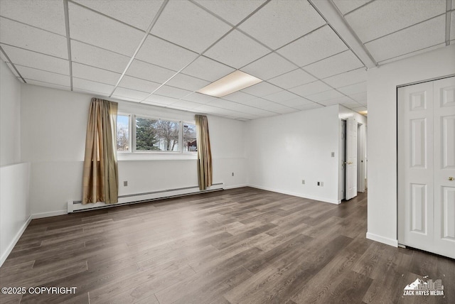 interior space with baseboards, a drop ceiling, baseboard heating, and wood finished floors
