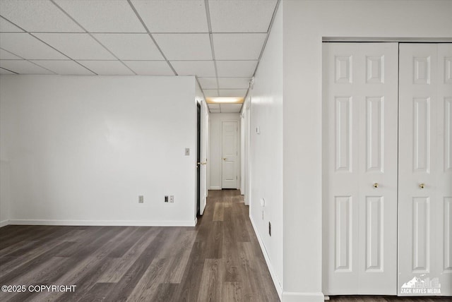 hall featuring dark wood-style flooring, baseboards, and a paneled ceiling