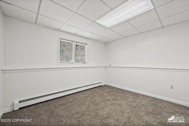basement with carpet floors, a baseboard radiator, a paneled ceiling, and baseboards