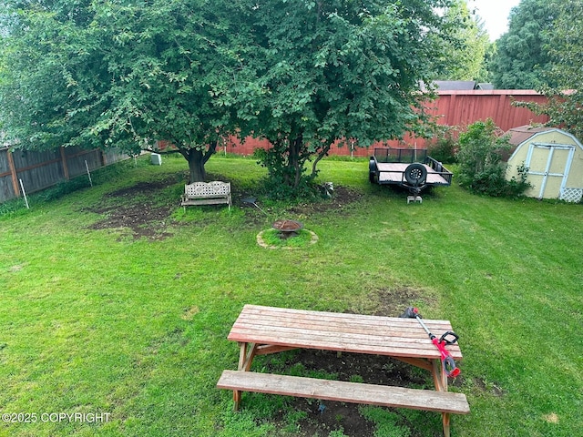 view of yard with fence, an outdoor structure, and a storage unit