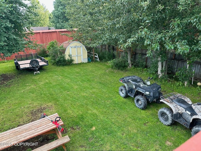 view of yard featuring an outdoor structure, a fenced backyard, and a storage unit