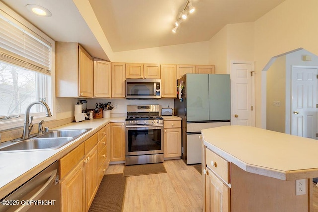 kitchen with stainless steel appliances, a sink, light brown cabinets, lofted ceiling, and light countertops