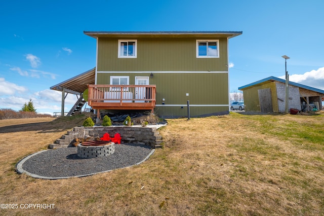 rear view of house featuring an outdoor fire pit, a wooden deck, and a yard