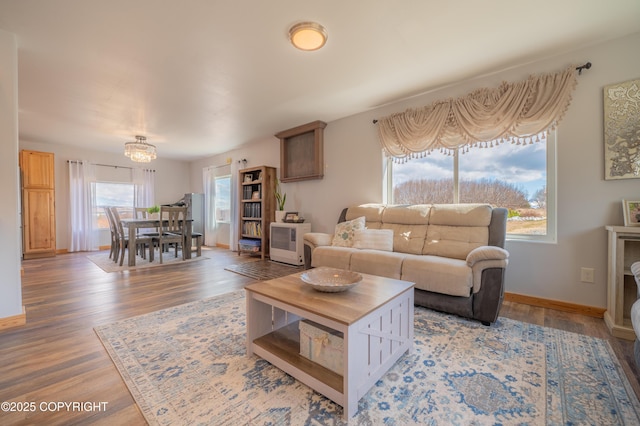 living area with light wood finished floors, a chandelier, and baseboards