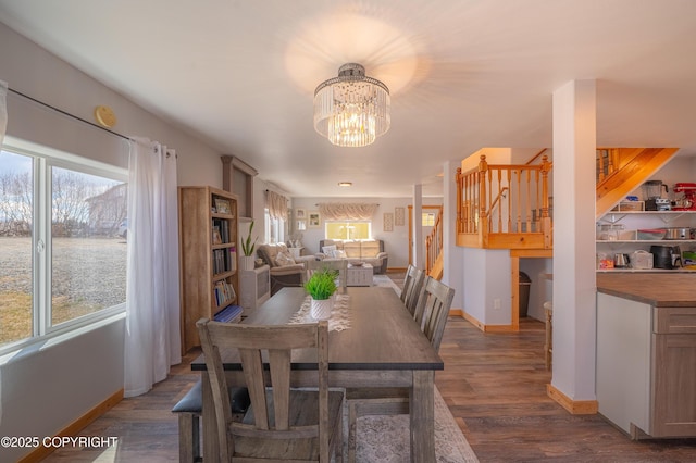 dining area featuring baseboards, a chandelier, stairs, and wood finished floors