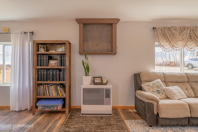 living area featuring heating unit, wood finished floors, and baseboards
